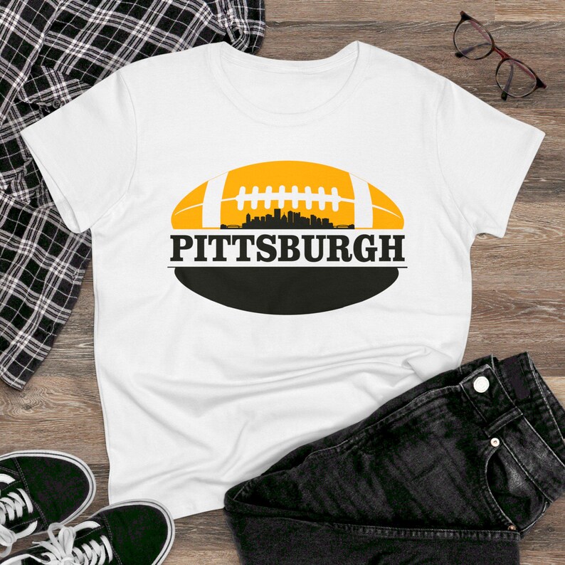 May include: White t-shirt with a black and yellow football graphic and the text "PITTSBURGH" printed on it.