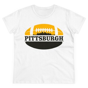 May include: White t-shirt with a yellow and black football graphic and the text "PITTSBURGH" printed on it.
