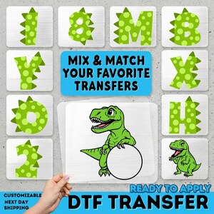 May include: A collection of green dinosaur-themed DTF transfers. The image includes letters and numbers with a dinosaur-spike design, a cartoon dinosaur, and the text "MIX & MATCH YOUR FAVORITE TRANSFERS" and "READY TO APPLY DTF TRANSFER".