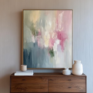 May include: A dark wood console table with four drawers and black metal legs. The table is decorated with a framed abstract painting with pink, blue, and green colors, and two white ceramic vases.