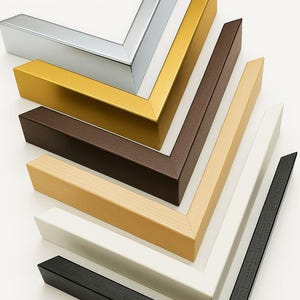 May include: A collection of picture frame corners in various colors, including silver, gold, brown, natural wood, white, and black. The frames are arranged in a diagonal pattern, showcasing their different finishes and styles.