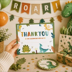May include: A rectangular thank you card featuring colorful cartoon dinosaur illustrations, green borders, and the text THANK YOU FOR CELEBRATING WITH US! The card includes small drawings of various dinosaurs, leaves, and bones on a white background.