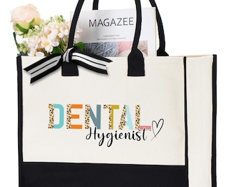 May include: A white canvas tote bag with black handles and a black bottom panel. The words "DENTAL Hygienist" are printed on the front in colorful letters. The bag contains a magazine, flowers, and a striped bow.