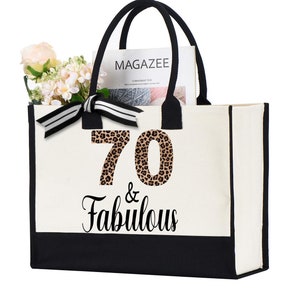 May include: A white canvas tote bag with black trim and handles. The bag has a leopard print number "70" and the text "& Fabulous" printed on it.