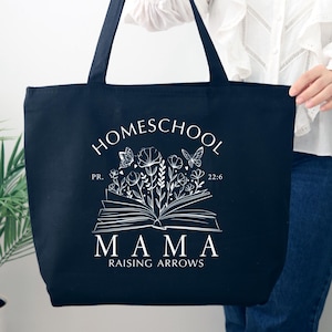 Puede incluir: Bolsa de lona negra con texto blanco que dice "Homeschool Mama Raising Arrows" con un dise&ntilde;o floral y un libro abierto con mariposas.