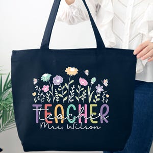 May include: Black canvas tote bag with a colorful floral design and the text "teacher mrs. wilson".
