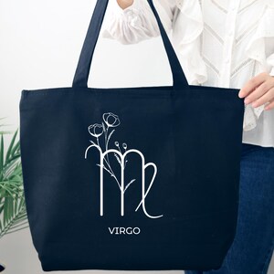 May include: Black canvas tote bag with a white floral design and the Virgo zodiac symbol. The text "VIRGO" is printed below the symbol.