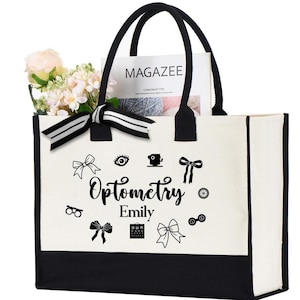 May include: A canvas tote bag with black handles and a black bottom panel. The bag features the word "Optometry" and the name "Emily" in a script font, along with eye-related graphics. The bag is filled with flowers and a magazine.
