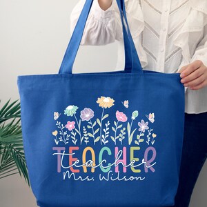 May include: A royal blue canvas tote bag with a colorful floral design and the text "Teacher Mrs. Wilson".