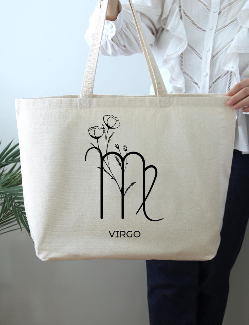 May include: A white canvas tote bag with black floral and zodiac design. The bag features a Virgo zodiac symbol with a floral design and the word "VIRGO" printed below.