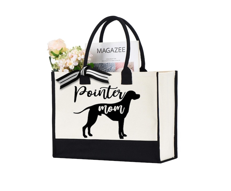 K&ouml;nnte beinhalten: Eine wei&szlig;e Canvas-Tragetasche mit schwarzem Besatz und Griffen. Die Tasche hat eine schwarze Silhouette eines Pointer-Hundes und den Text "Pointer mom" auf der Vorderseite.