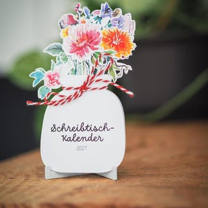 Nahaufnahme des Tischkalenders mit dem Deckblatt und der rot-weißen Schleife.
