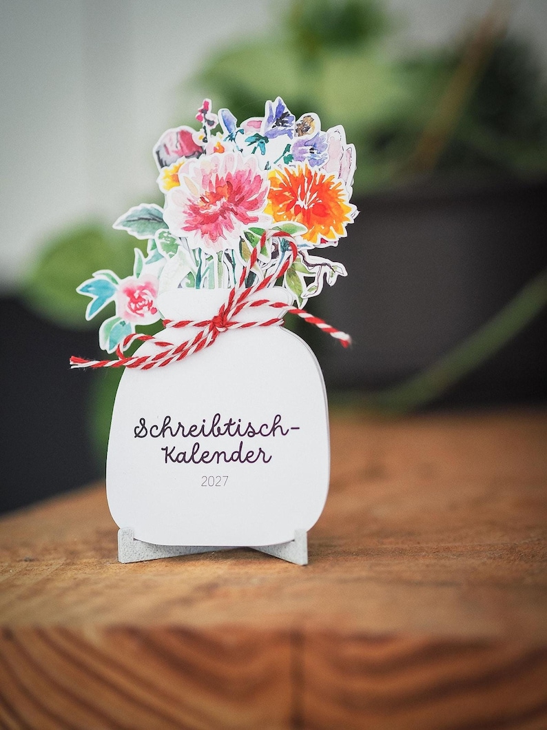 Nahaufnahme des Tischkalenders mit dem Deckblatt und der rot-weißen Schleife.