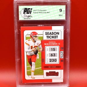 Peut inclure: Carte de football Patrick Mahomes II de la série Contenders 2021, classée et encadrée dans un étui protecteur. La carte présente Mahomes en uniforme des Chiefs et comprend un design "Season Ticket". La carte est classée 9 "Mint" par Pristine Grading International.