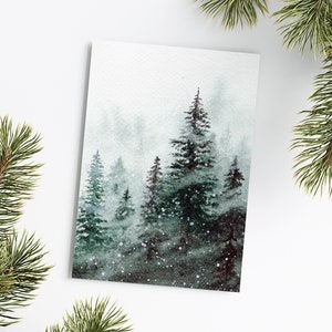 May include: A rectangular art print featuring a watercolor painting of a dense forest with dark green pine trees set against a misty, light gray background. Small white dots are scattered throughout the scene to represent falling snow.