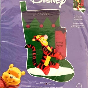 May include: Disney Tigger's Presents felt applique kit. The kit features a Christmas stocking design with Tigger and Winnie the Pooh. The finished size is approximately 18 inches diagonally. The kit includes screen-printed acrylic felt, floss, and instructions.