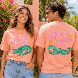 Peut inclure: Un t-shirt couleur pêche avec un motif d'alligator vert et le texte "LATER" sur le devant et "AFTER WHILE" au dos, agrémenté d'étoiles roses et jaunes. Le t-shirt est porté avec un jean en denim bleu.