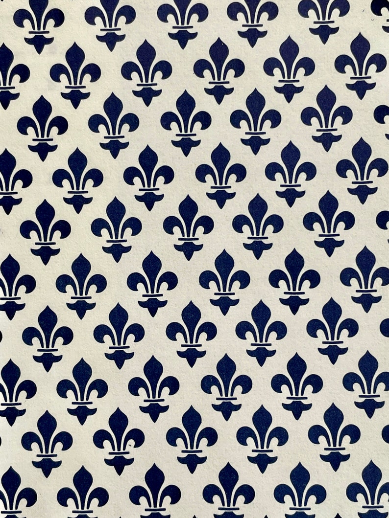 Puede incluir: Un patr&oacute;n repetido de s&iacute;mbolos de flor de lis azul marino sobre un fondo crema. El dise&ntilde;o est&aacute; espaciado uniformemente, creando una est&eacute;tica sim&eacute;trica y cl&aacute;sica. La imagen es una vista de cerca del patr&oacute;n.