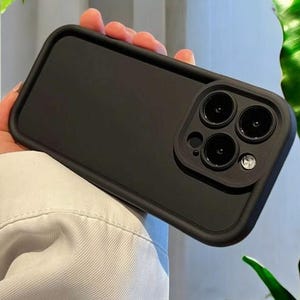 May include: Black phone case with a raised camera lens cover. The case has a smooth, matte finish.