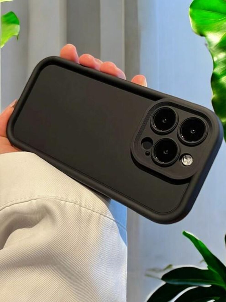May include: Black phone case with a raised camera lens cover. The case has a smooth, matte finish.
