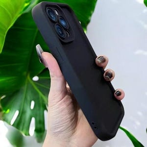 May include: A black phone case with a raised camera lens protector. The case has a smooth, matte finish.