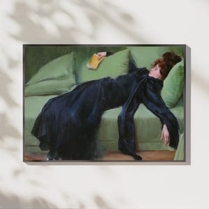 May include: A framed art print of a woman reclining on a green sofa, holding a book. The woman is wearing a long, dark blue dress. The artwork has a classic, painterly style with soft lighting and muted colors.