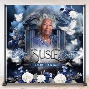 May include: A memorial backdrop featuring a portrait of an elderly woman, Susie Burton, with the dates 3.26.1951 - 9.12.2023. The design includes blue floral accents, doves, and the names Olga Susie Burton in elegant script.