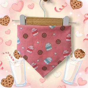May include: Pink dog bandana with a pattern of milk cartons and chocolate chip cookies. The bandana is hanging on a wooden hanger. The background has hearts and cookies.