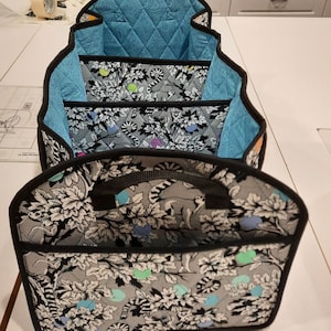 May include: A set of three fabric storage bins with black trim and handles. The bins are lined with a blue quilted fabric and feature a black and white print of leaves and animals.