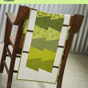 May include: A quilting pattern for a table runner or bed runner featuring a design of green trees with brown branches. The pattern is called "Tumbling Trees" and is from "The Fat Quarter Gypsy".