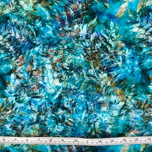 May include: Teal fabric with a blue and brown leafy pattern. The fabric has a watercolor effect and is perfect for crafting projects.