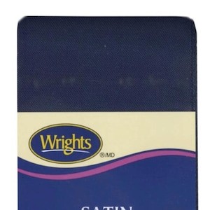 May include: A navy blue satin ribbon spool featuring a cream-colored label with the brand name Wrights in yellow text inside a blue oval. The label includes a purple wavy line design and the word SATIN printed in white capital letters below.
