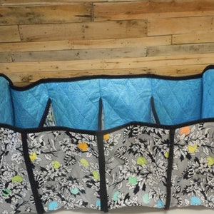 May include: A black and white fabric storage organizer with a blue quilted lining. The organizer has four compartments and is divided by black fabric.