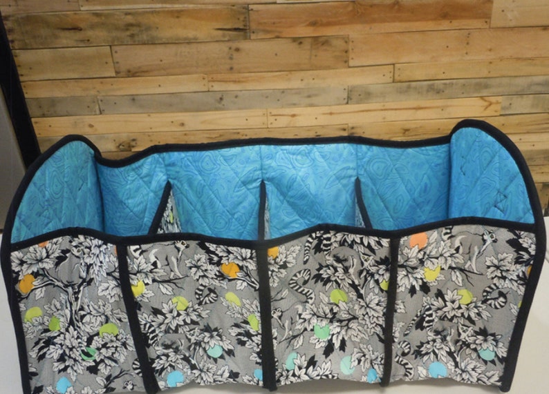 May include: A black and white fabric storage organizer with a blue quilted lining. The organizer has four compartments and is divided by black fabric.