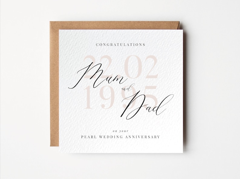 May include: A square greeting card with a textured white surface and a brown envelope. The card reads "Congratulations Mum and Dad" in elegant script, with the date "22.02.1995" in a soft pink hue. The text "on your Pearl Wedding Anniversary" is also included.