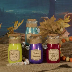 May include: Four small glass bottles with cork stoppers and twine tied around the necks. The bottles are filled with different colored liquids and have labels with the following text: "Star Dust", "Pixie Dream", "Vampire Flesh", and "Love Potion".