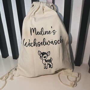 May include: A white drawstring bag with the text "Medine's Wechselwäsche" and a black and white illustration of a deer.