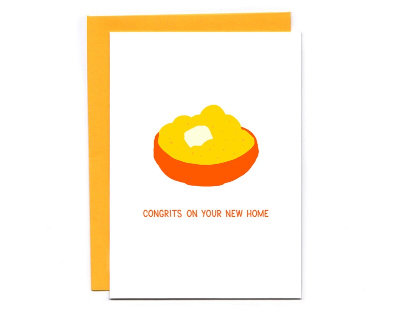May include: A white card with an orange bowl of yellow grits and a pat of butter. The text "CONGRITS ON YOUR NEW HOME" is printed in black below the bowl.