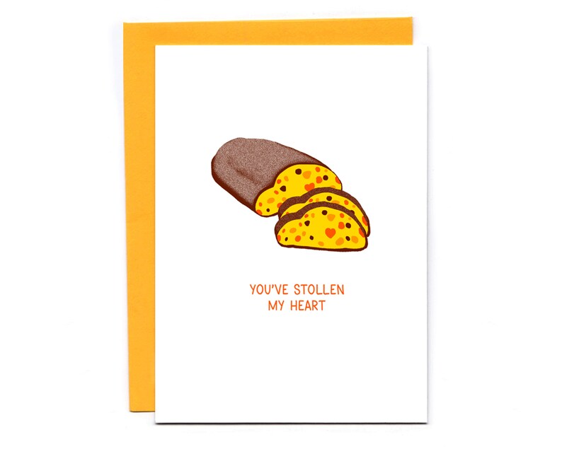 Puede incluir: Una tarjeta blanca con una ilustraci&oacute;n marr&oacute;n y amarilla de un pan de frutas. El texto "You've Stollen My Heart" est&aacute; impreso debajo de la ilustraci&oacute;n.