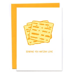 May include: A white card with a yellow border and a drawing of matzah on it. The text "Sending you matzah love" is printed on the card.