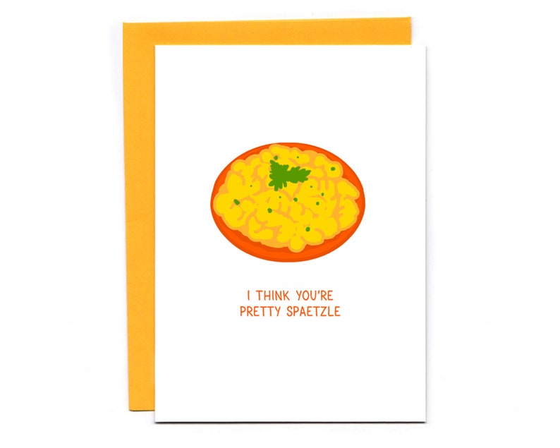 May include: A white card with a yellow and orange illustration of a bowl of spaetzle. The text on the card reads "I think you're pretty spaetzle."