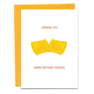 May include: A white card with orange text that says "Sending you warm birthday knishes". There is a yellow illustration of two knishes.