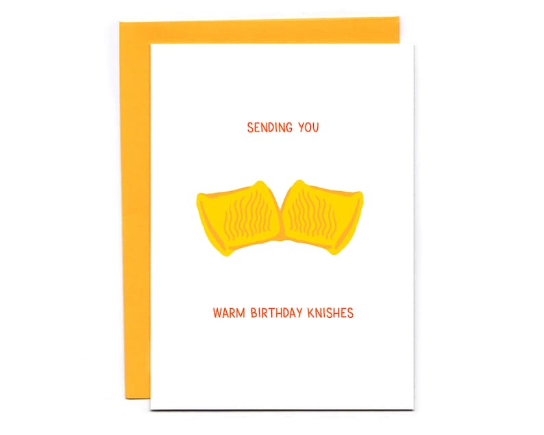 May include: A white card with orange text that says "Sending you warm birthday knishes". There is a yellow illustration of two knishes.