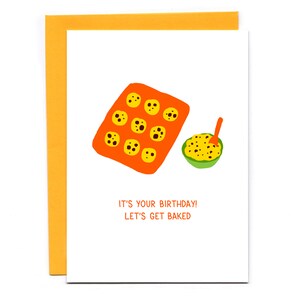 May include: A white card with an orange baking sheet filled with chocolate chip cookies and a green bowl of cookie dough. The text on the card reads "It's your birthday! Let's get baked."