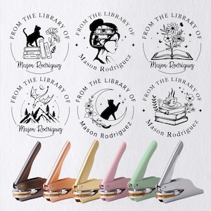 May include: A collection of personalized library seals with various designs, including a cat, a woman with books, and flowers. The seals come in several colors, including brown, rose gold, gold, pink, green, and silver.