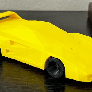 Puede incluir: Un coche de juguete amarillo con ruedas negras. El coche es un modelo de un coche deportivo clásico.