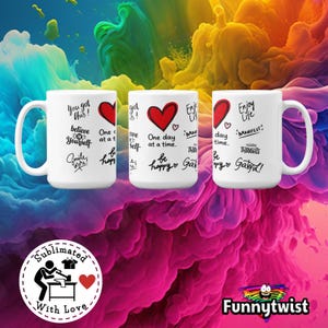 May include: Three white ceramic mugs with inspirational quotes and a red heart design. The mugs feature phrases like "You got this!", "Believe in Yourself", and "Enjoy Life". The background is a colorful, abstract design.
