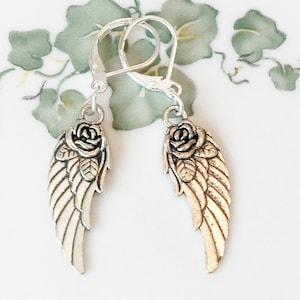 May include: Silver dangle earrings with a rose and angel wing design.