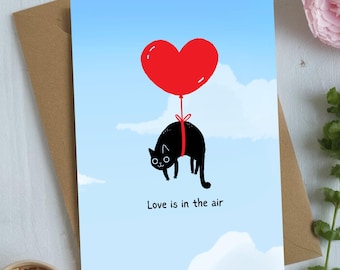 Tarjeta de felicitación de San Valentín con un gato volando con un globo en forma de corazón / El amor está en el aire
