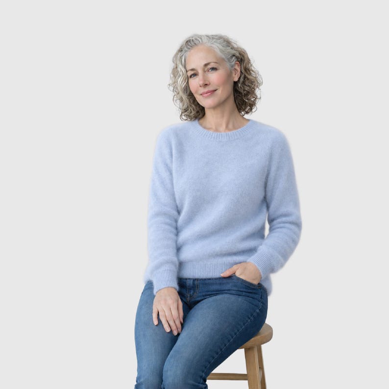 May include: A light blue long-sleeved jumper with a crew neckline and a soft, fuzzy texture, paired with classic blue denim jeans. The jumper features ribbed cuffs and a ribbed hem, providing a clean and simple look for everyday wear.